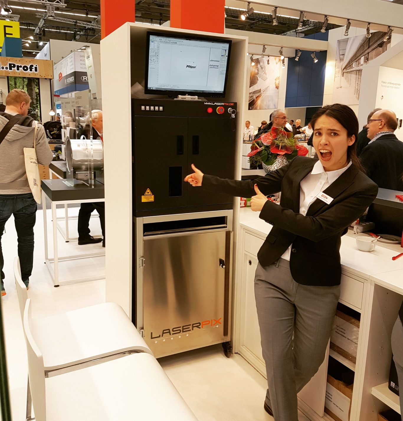 Eine Person präsentiert ein Gerät am Messestand, umgeben von interessierten Besuchern.