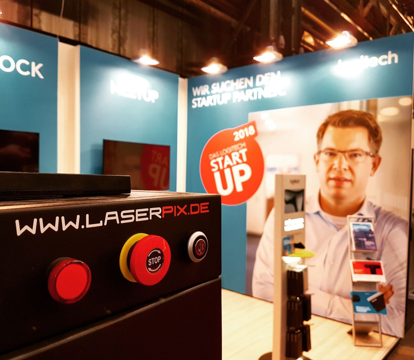 Messestand mit Lasergerät und einem Mann, der hinter einem Banner steht.