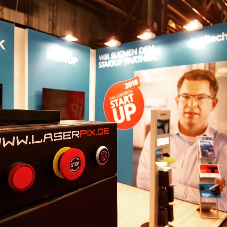 Stand von Laserpix am Messestand mit Geräten und prominenter Werbung.